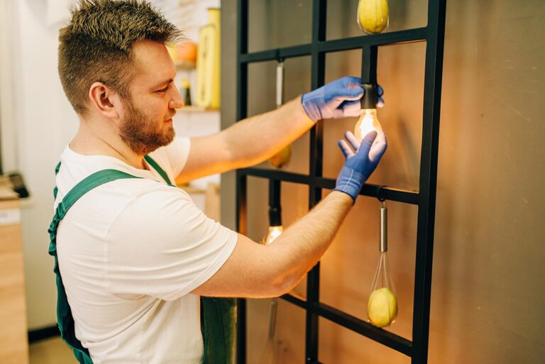 Worker replacing a light bulb in a wall fixture