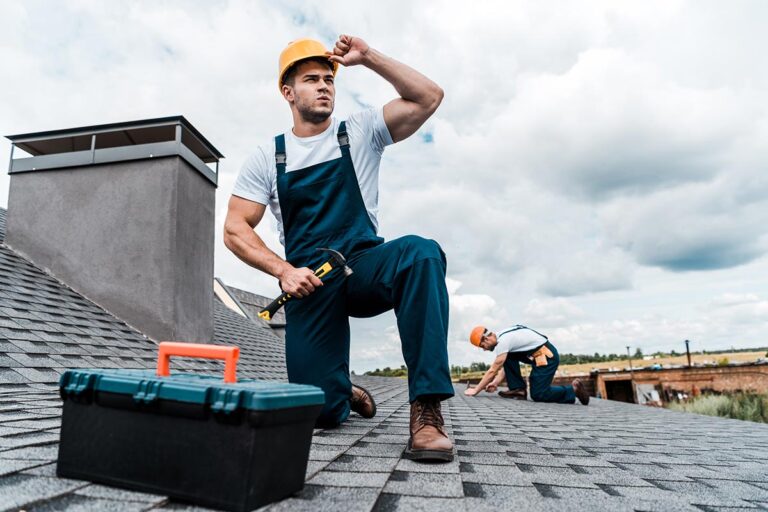 Two workers repairing a shingled roof